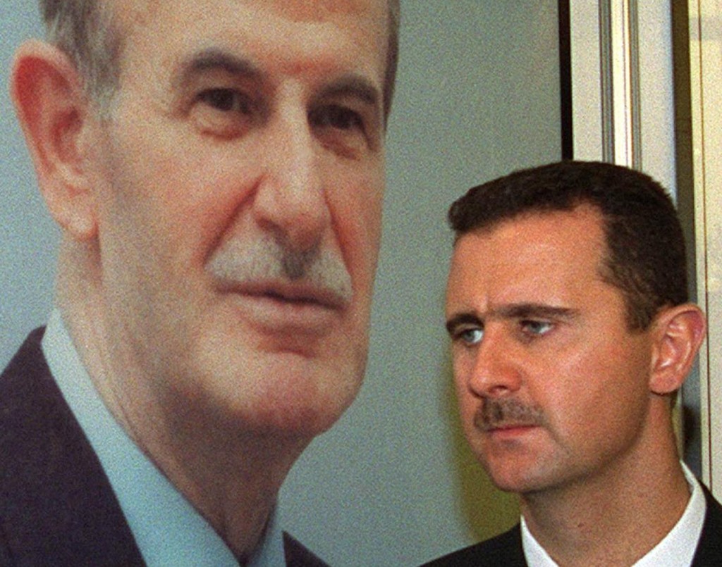 DAMASCUS, SYRIA: Bashar al-Assad, son of Syrian President Hafez al-Assad, stands under a portrait of his father 24 April 2000 in Damascus. (Photo credit should read LOUAI BESHARA/AFP/Getty Images)
